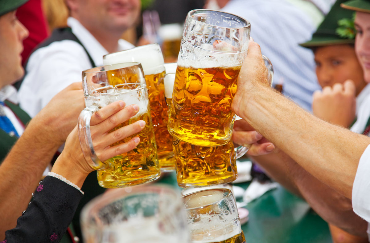 An Oktoberfest beer toast by festival crowds wearing lederhosen.