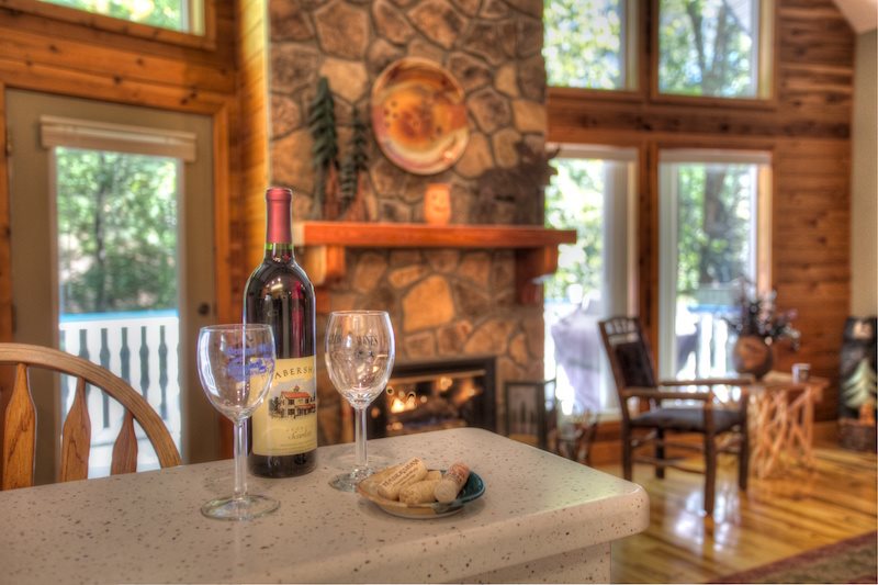 Wine and wine glasses near the fireplace at Misty Creek Cabin.